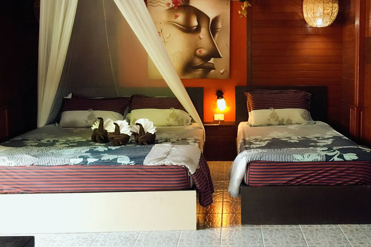 Ein Zimmer mit zwei Betten, einem Himmelsbett, einer Wandleuchte und einer Wanddekoration.