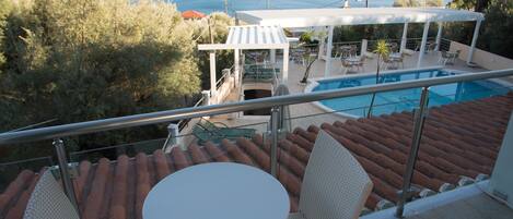 A terrace with a pool, outdoor seating, and a view of the sea.