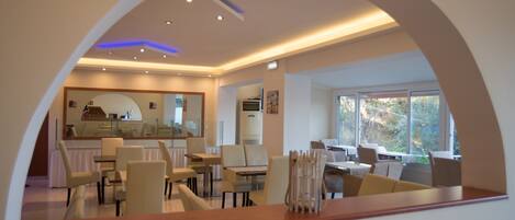 A modern dining area with a curved ceiling, large windows, and a central seating arrangement.