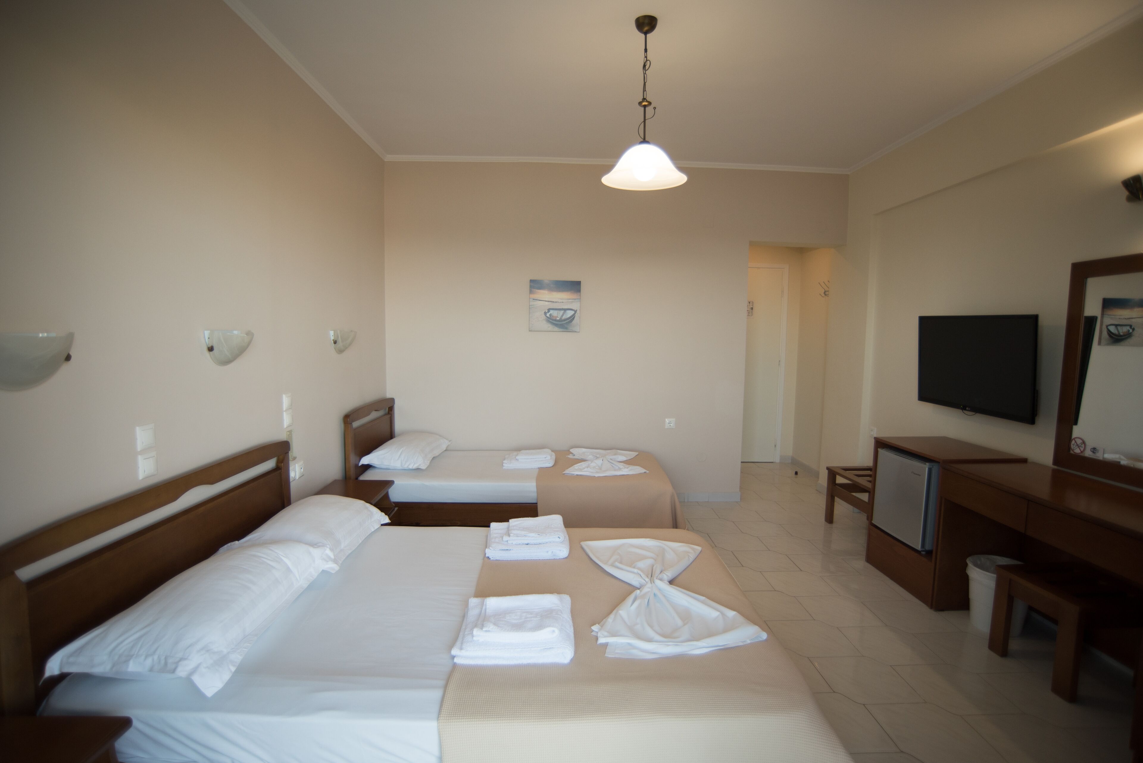 Une chambre d’hôtel avec deux lits, une télévision, un bureau et un miroir.
