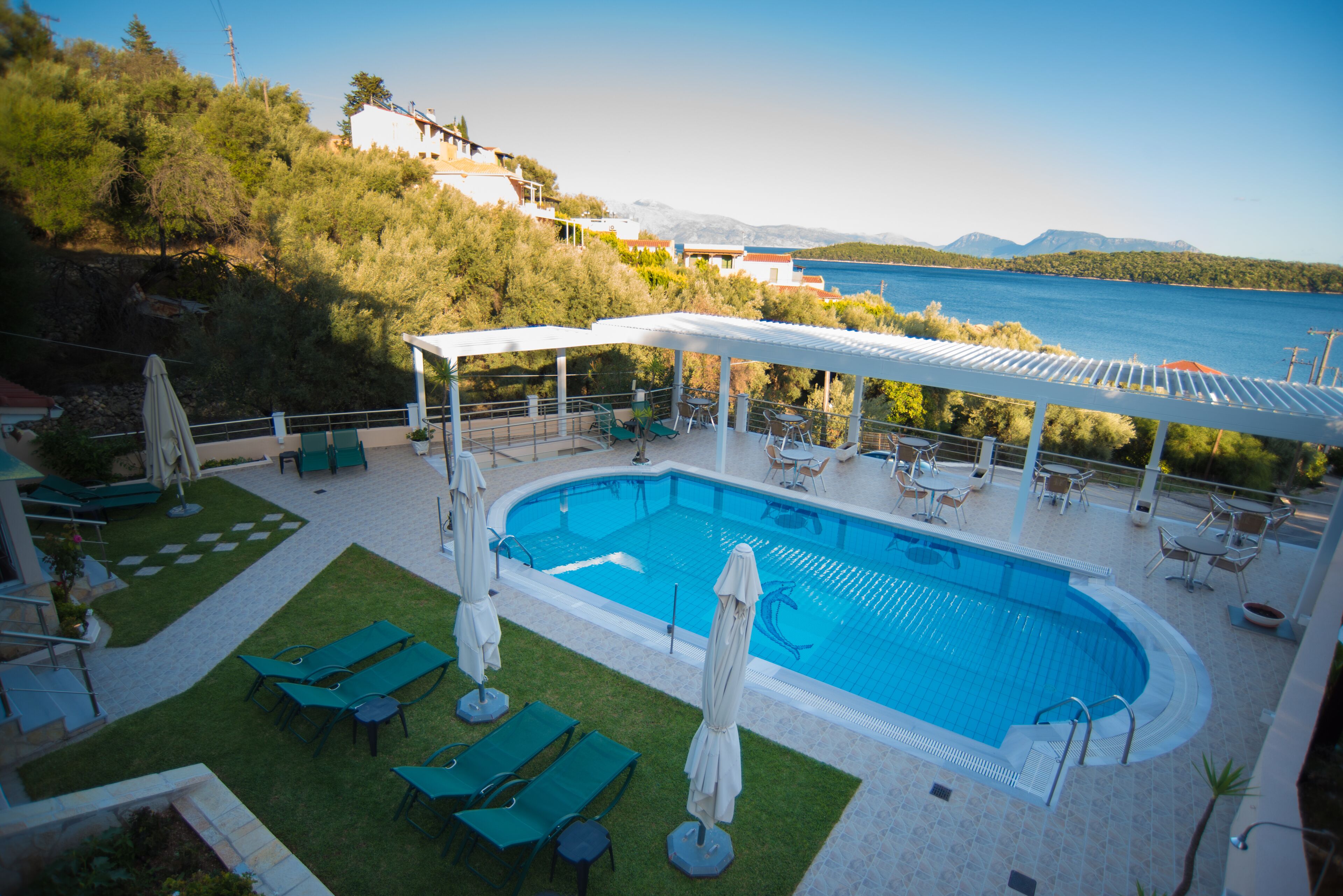A swimming pool with lounge chairs and umbrellas, surrounded by a covered patio area with tables and chairs.