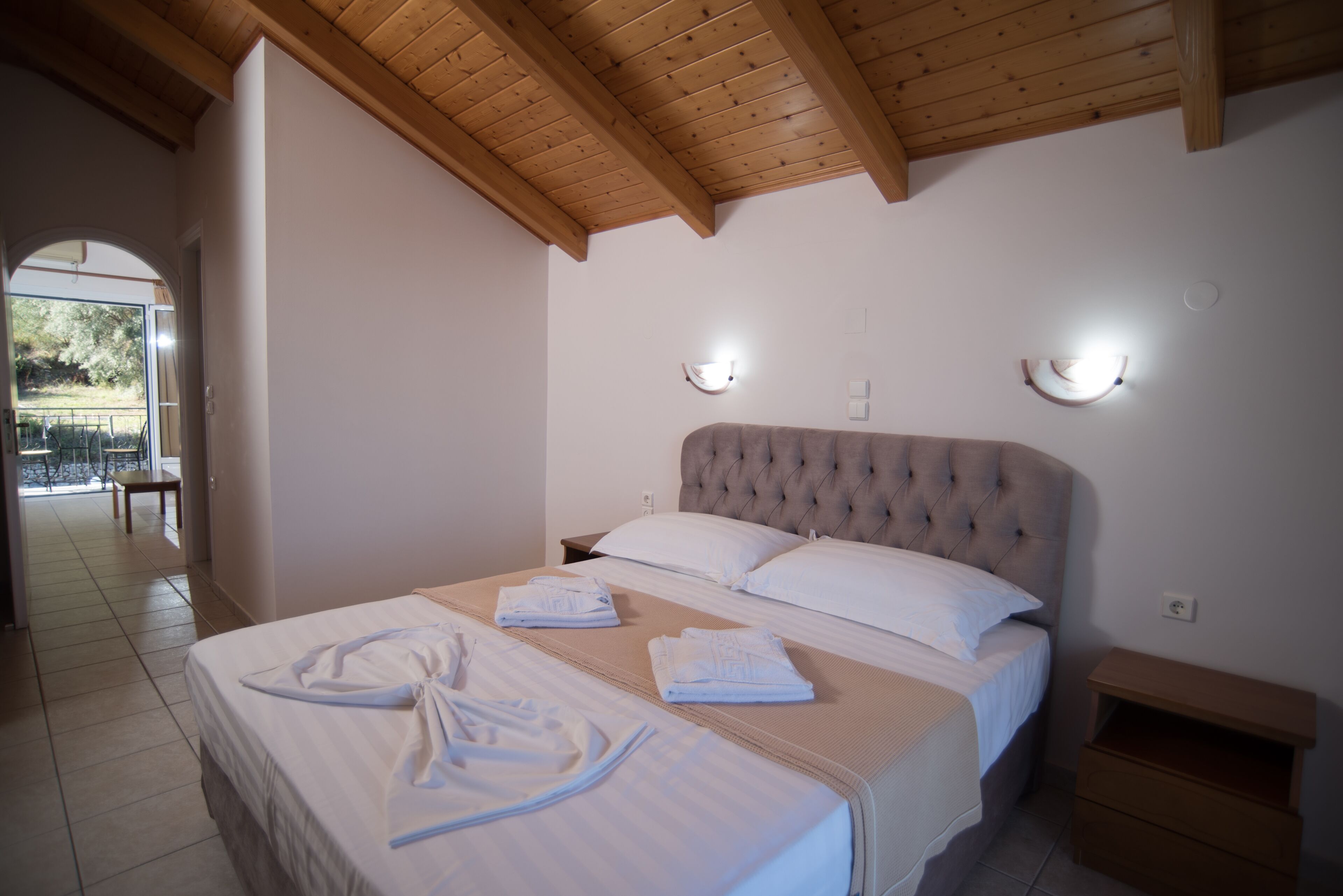 A bedroom with a large bed, two bedside tables, and a wooden ceiling.