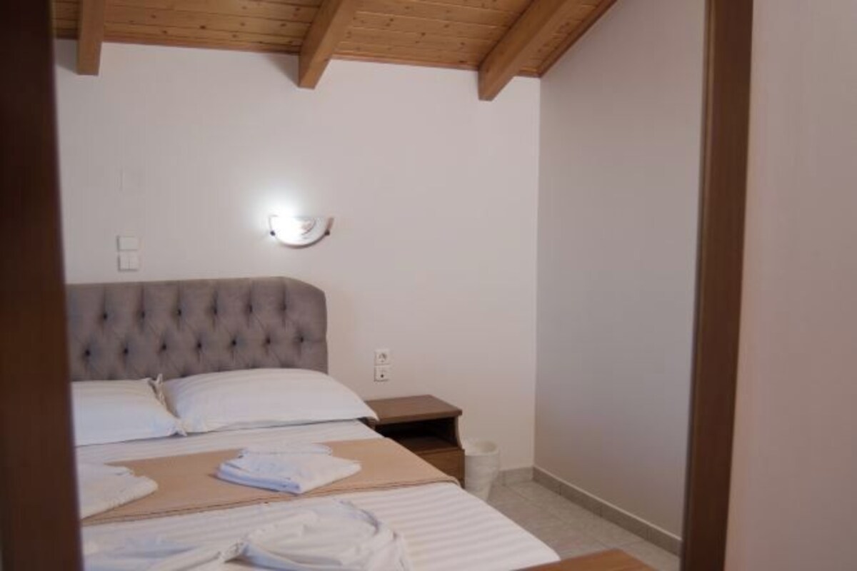 Une chambre à coucher avec une tête de lit capitonnée, une table de chevet et un luminaire fixé au mur.