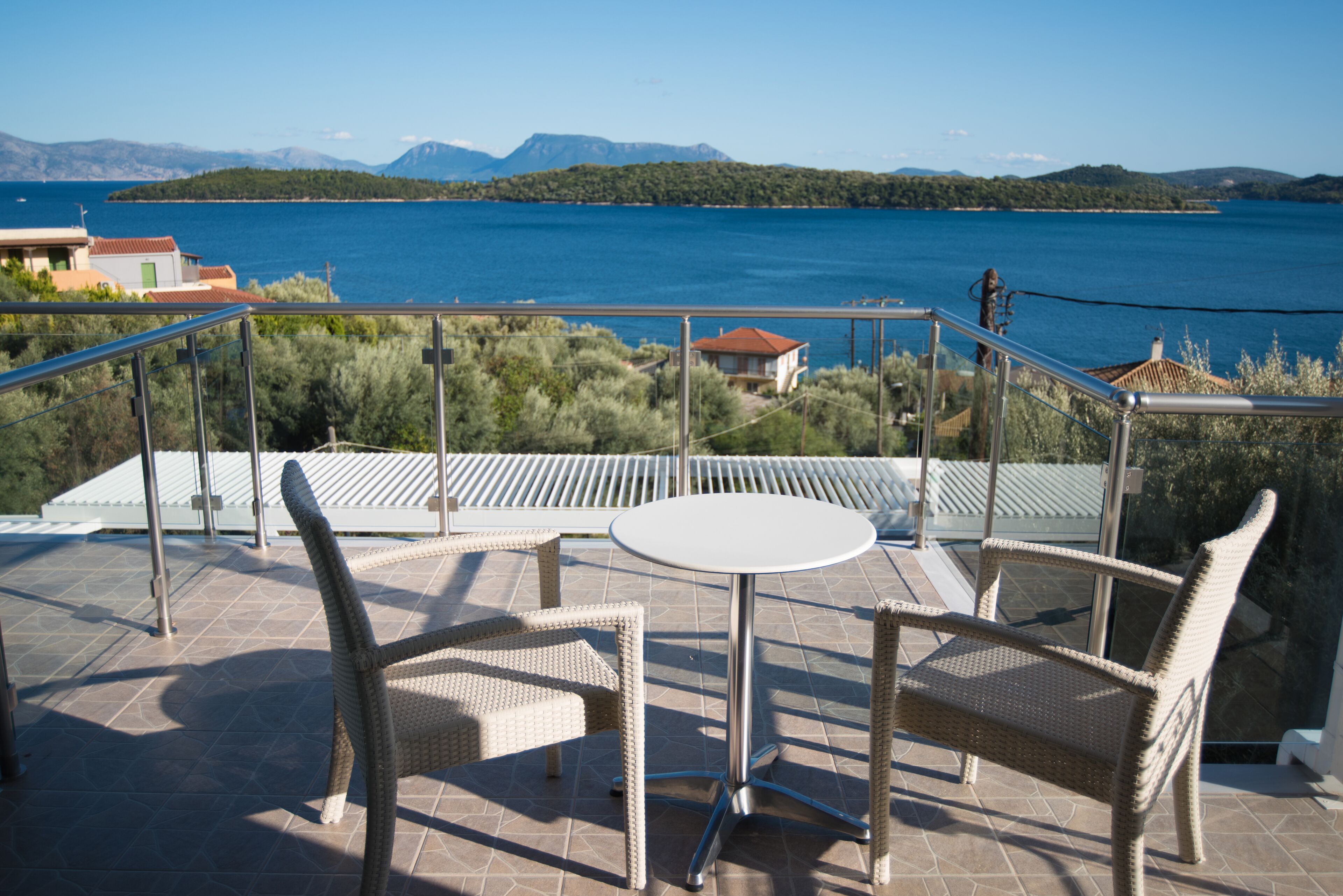 A terrace with wicker furniture and a view of a lake and mountains.