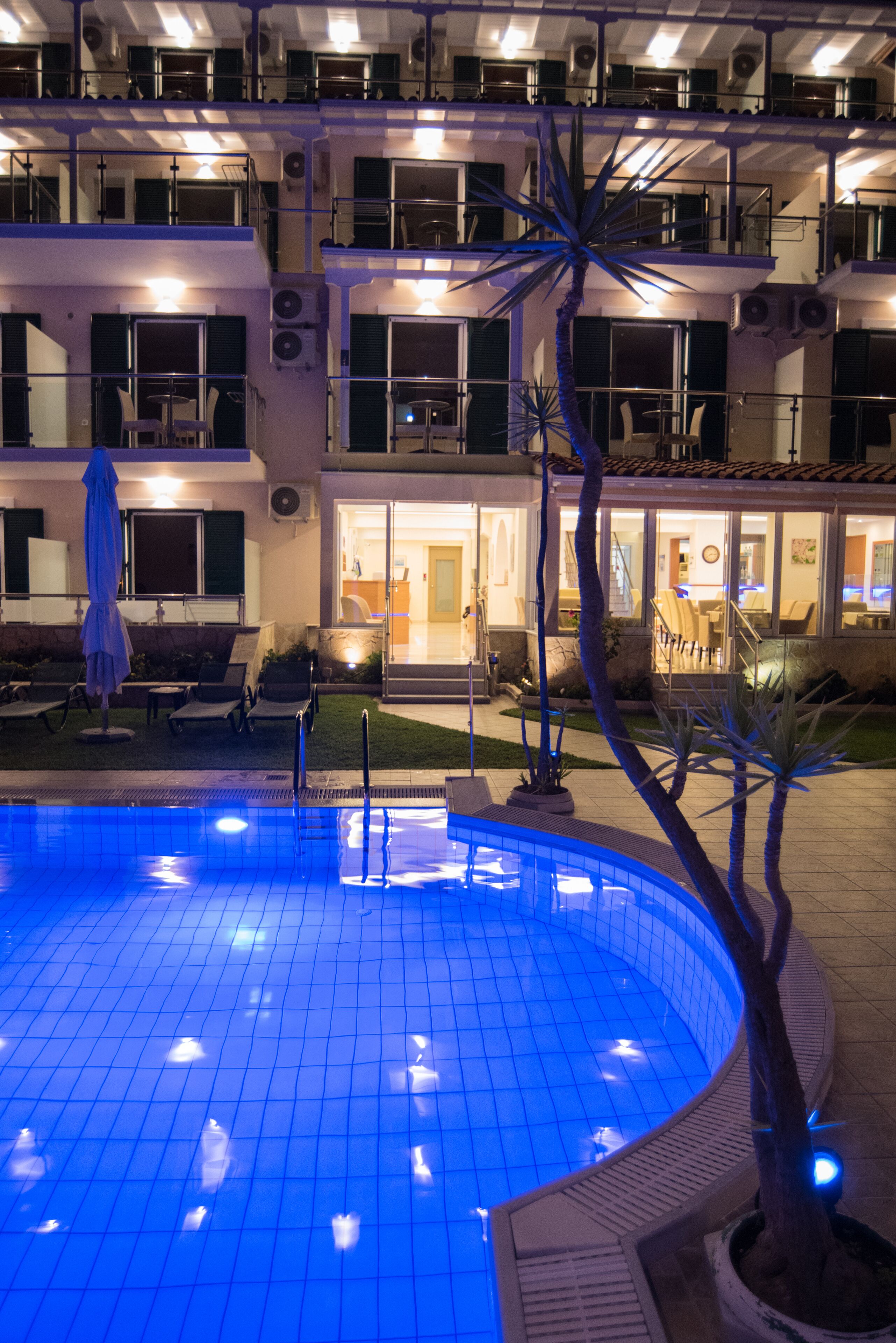 A hotel with a swimming pool, outdoor seating, and multiple balconies.