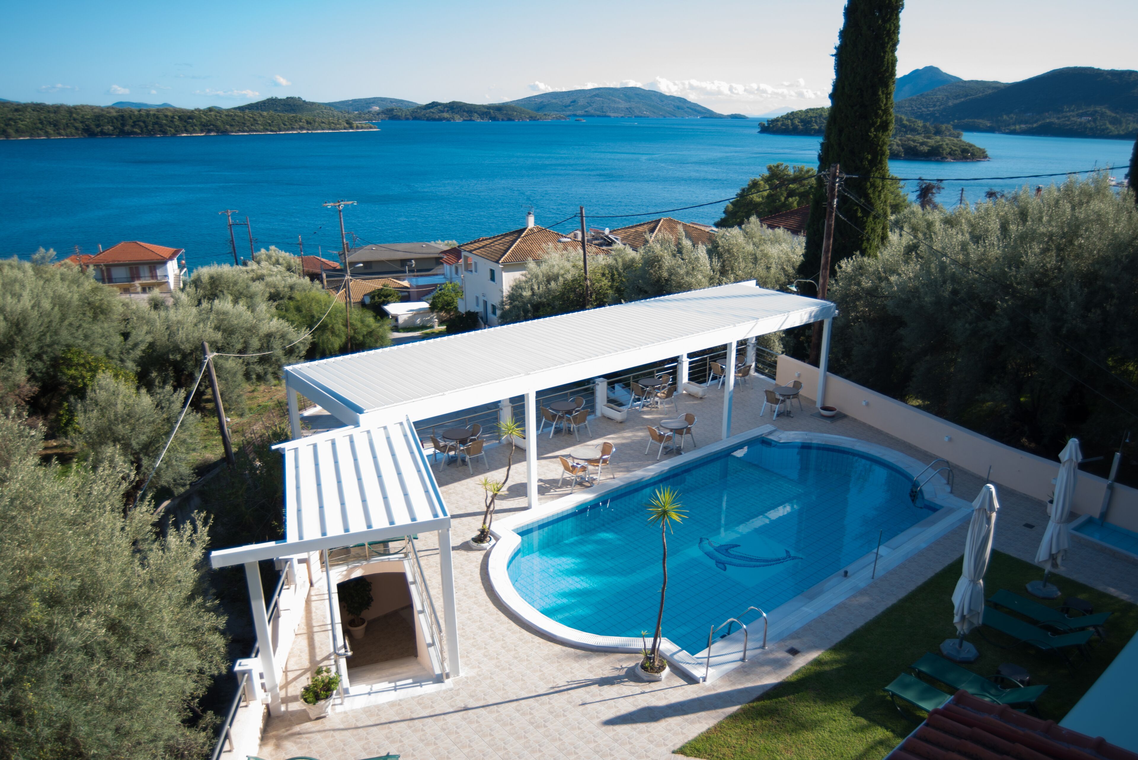 A swimming pool with a covered area, lounge chairs, and a view of the sea.