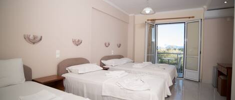 A hotel room with three beds, a balcony, and a view of the outdoors.