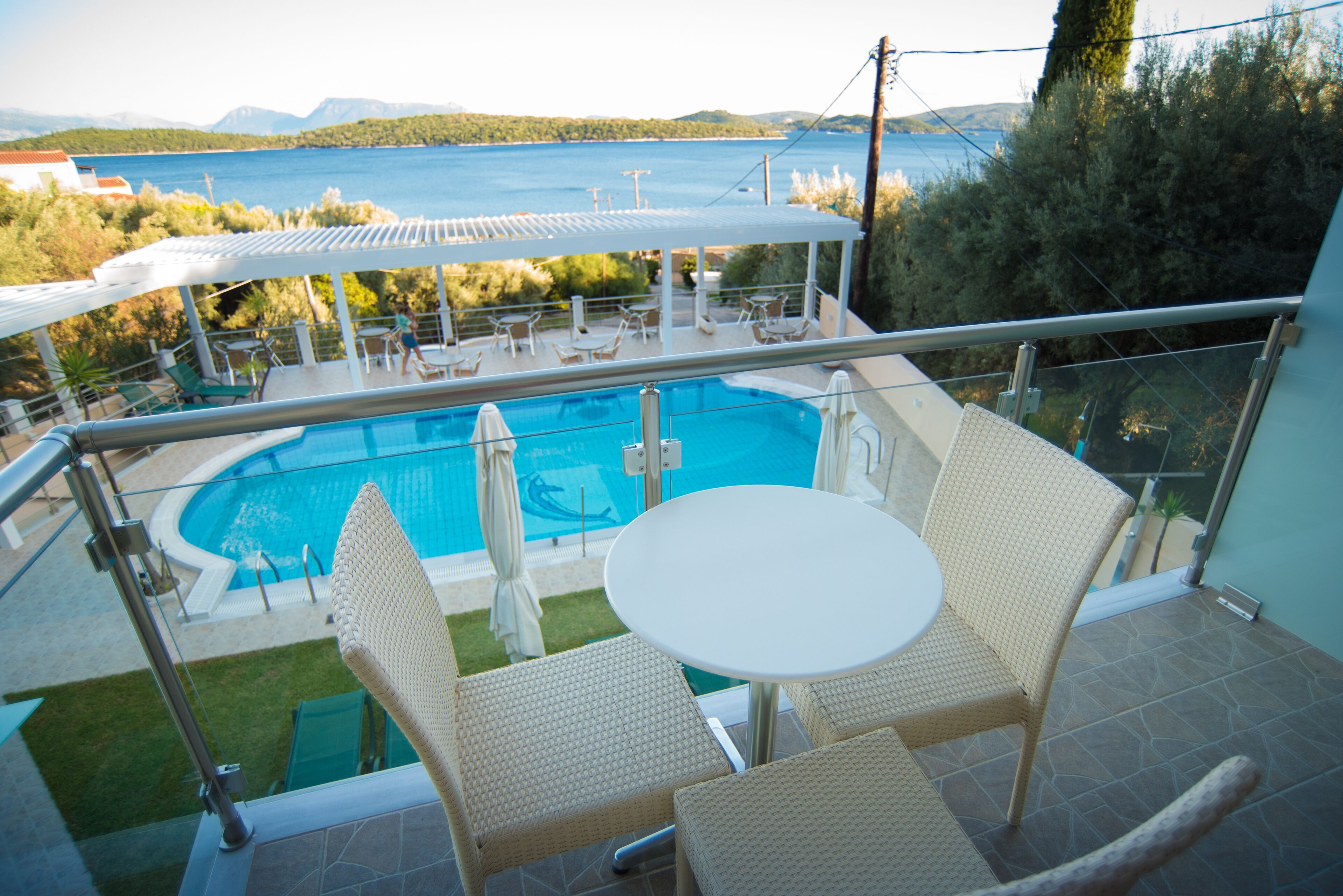 A balcony with a pool, wicker furniture, and a view of the sea.