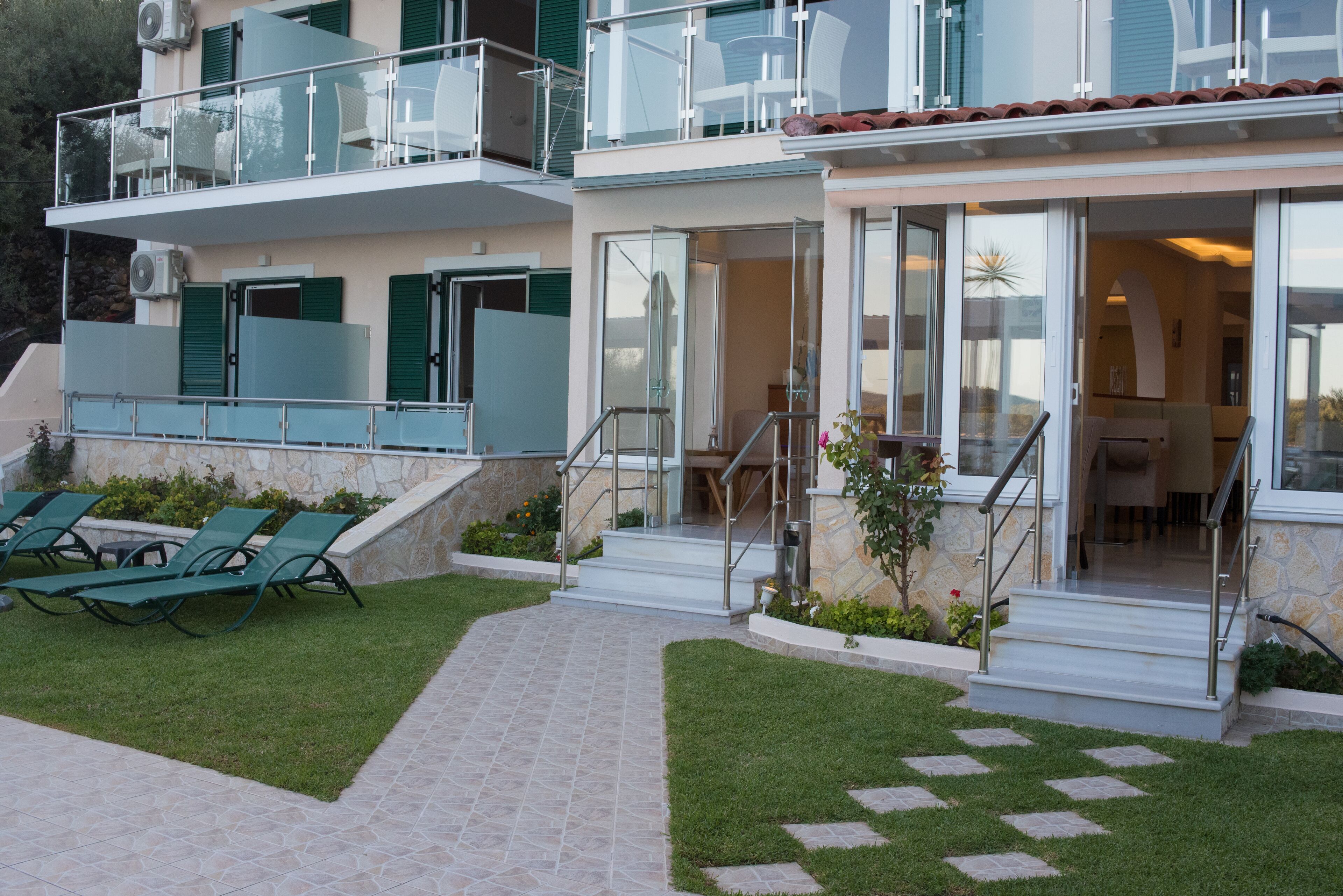 A modern two-story building with a balcony, outdoor seating, and a stone facade.