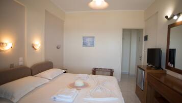 Una habitación de hotel con cama, lámparas de noche, televisión, escritorio y espejo.