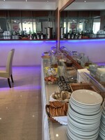 Uma mesa de buffet com diversos alimentos, utensílios e copos.