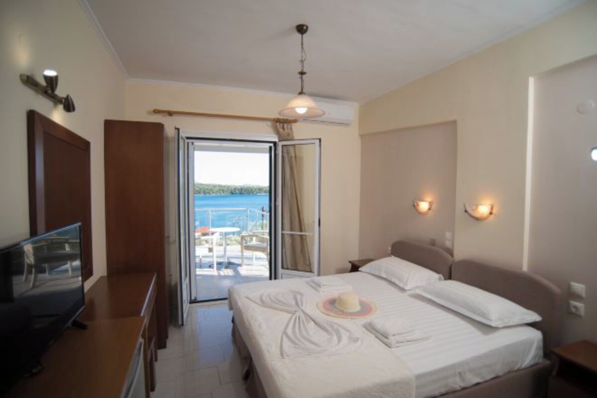Une chambre d’hôtel avec un lit, une télévision, un balcon avec vue et un ventilateur de plafond.