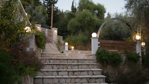 A stone staircase leading up a hill, surrounded by greenery and a wooden fence. - Oasis Hotel (Lefkada)