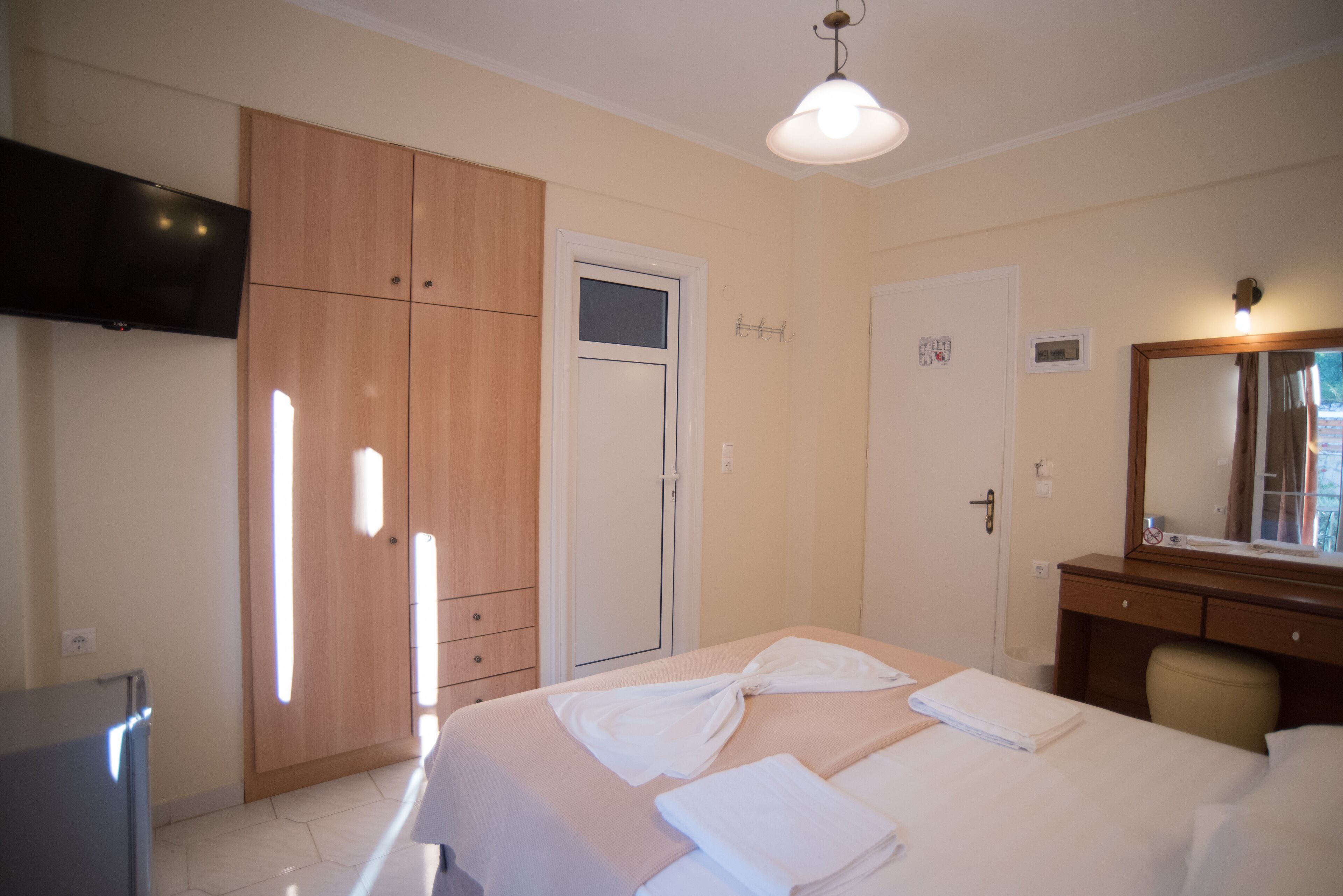 A hotel room with a bed, a TV, a wardrobe, and a mirror.