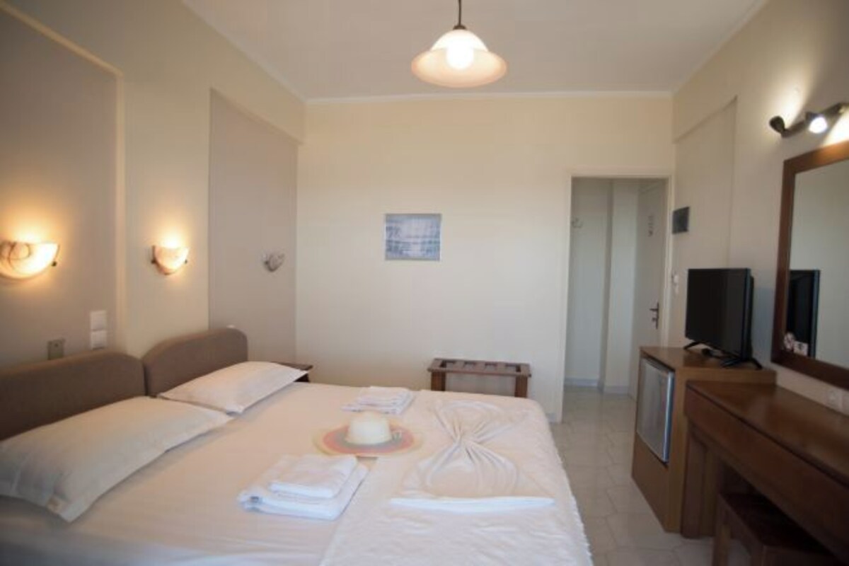 A hotel room with a bed, bedside lamps, a television, a mirror, and a small table.