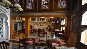 A restaurant with wooden furniture, stone walls, and framed artwork on the walls.