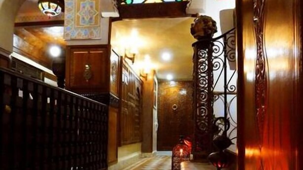 A hallway with a tiled floor, a staircase, and a decorative stained glass window.