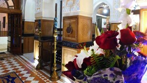 A room with a checkered floor, wooden furniture, and a floral arrangement.