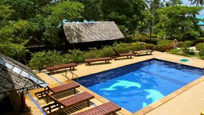 A swimming pool with wooden loungers and a thatched-roof structure. - Hinkong Hut (Ko Pha-ngan)