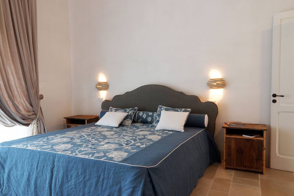 Un dormitorio con una cama, dos mesitas de noche y una puerta.