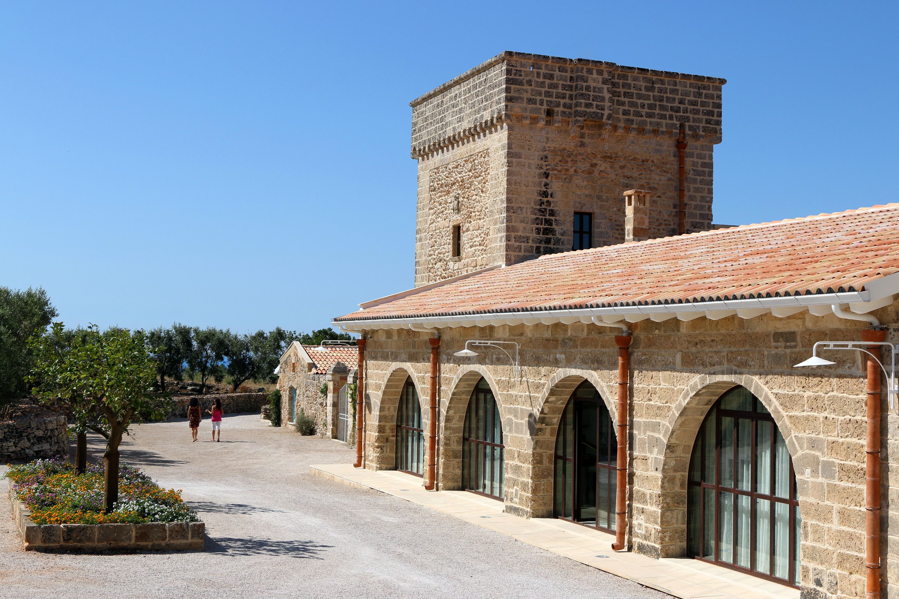 Um edifício de pedra com telhado em telhas, janelas em arco e uma torre.