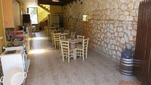 A dining area with stone walls, wooden tables, and chairs. - La Casa D' Irene (Lefkada)