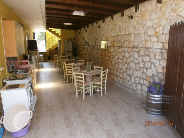 A dining area with stone walls, wooden tables, and chairs. - La Casa D' Irene (Lefkada)