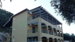 A two-story building with a stone facade, multiple balconies, and outdoor seating. - La Casa D' Irene (Lefkada)