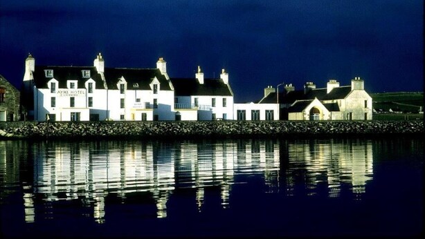 A row of white buildings with chimneys, reflecting on the water. - The Ayre Hotel (Kirkwall)