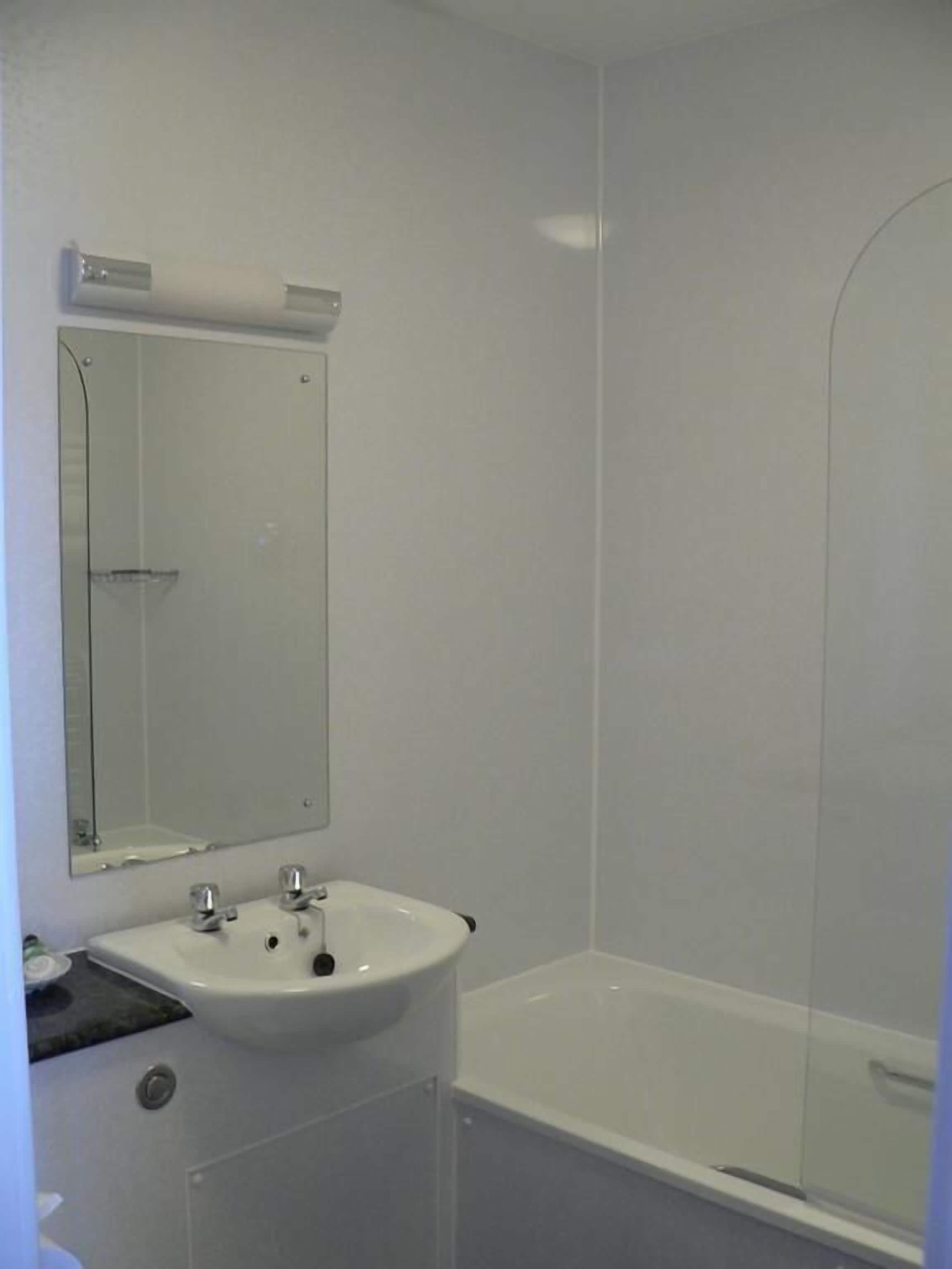 Ein Badezimmer mit Waschbecken, Spiegel und Badewanne.