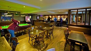 A billiards room with tables, chairs, and a bar area with patrons. - The Ayre Hotel (Kirkwall)