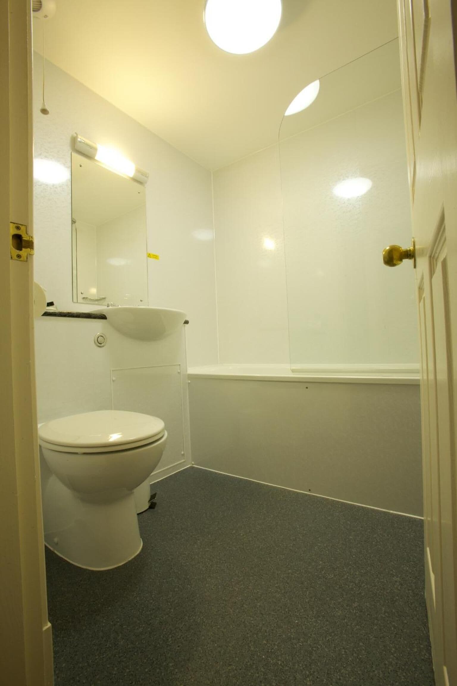 A bathroom with a toilet, sink, and mirror.