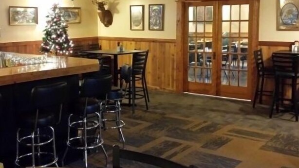 A bar area with stools, a Christmas tree, and framed pictures on the walls.