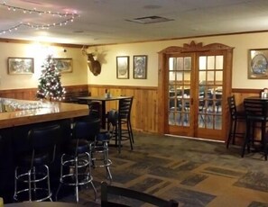 A bar area with stools, a Christmas tree, and framed pictures on the walls. - Inn of the Pines (Friendship)
