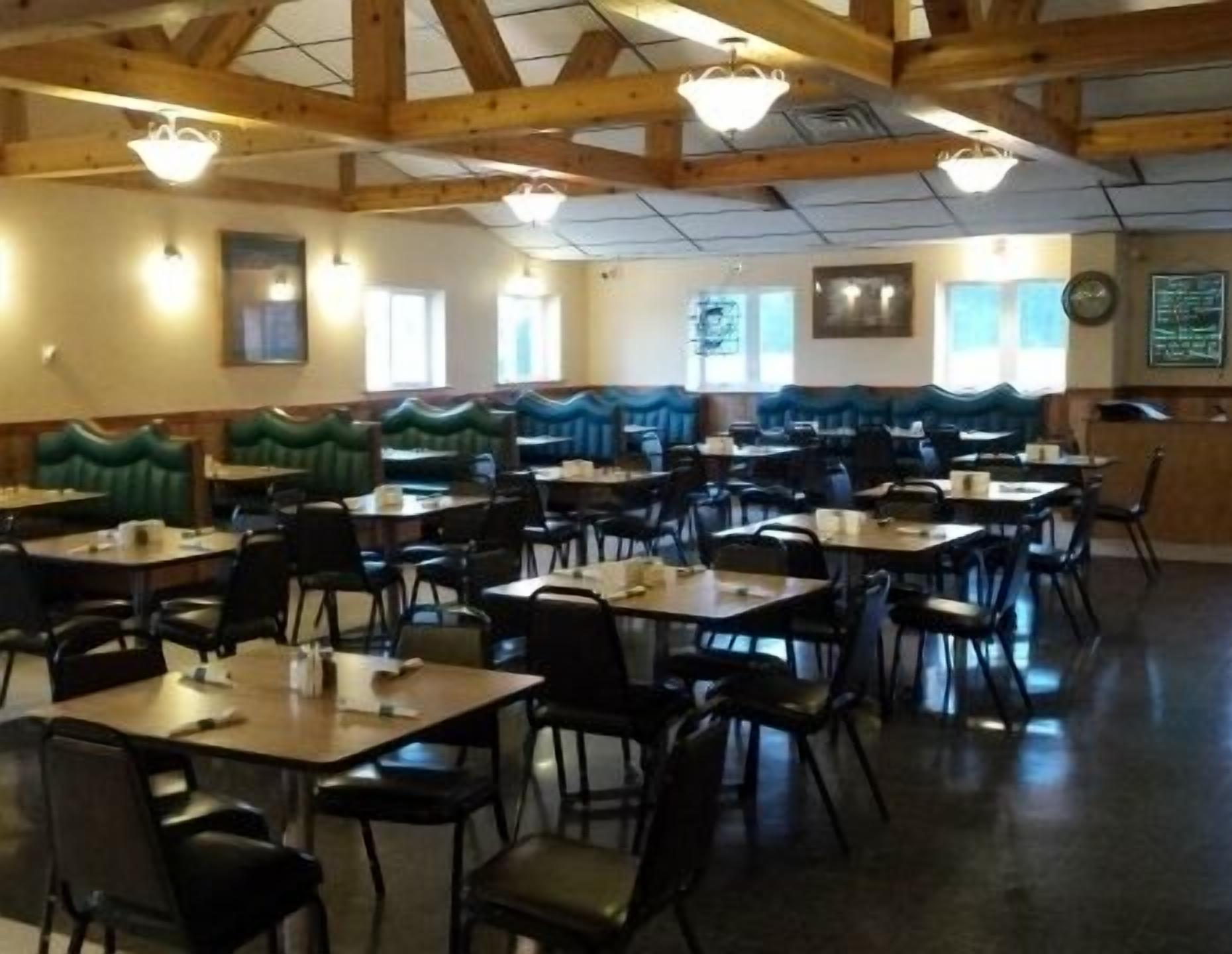 A dining area with booths and tables, wooden beams on the ceiling, and a clock on the wall.