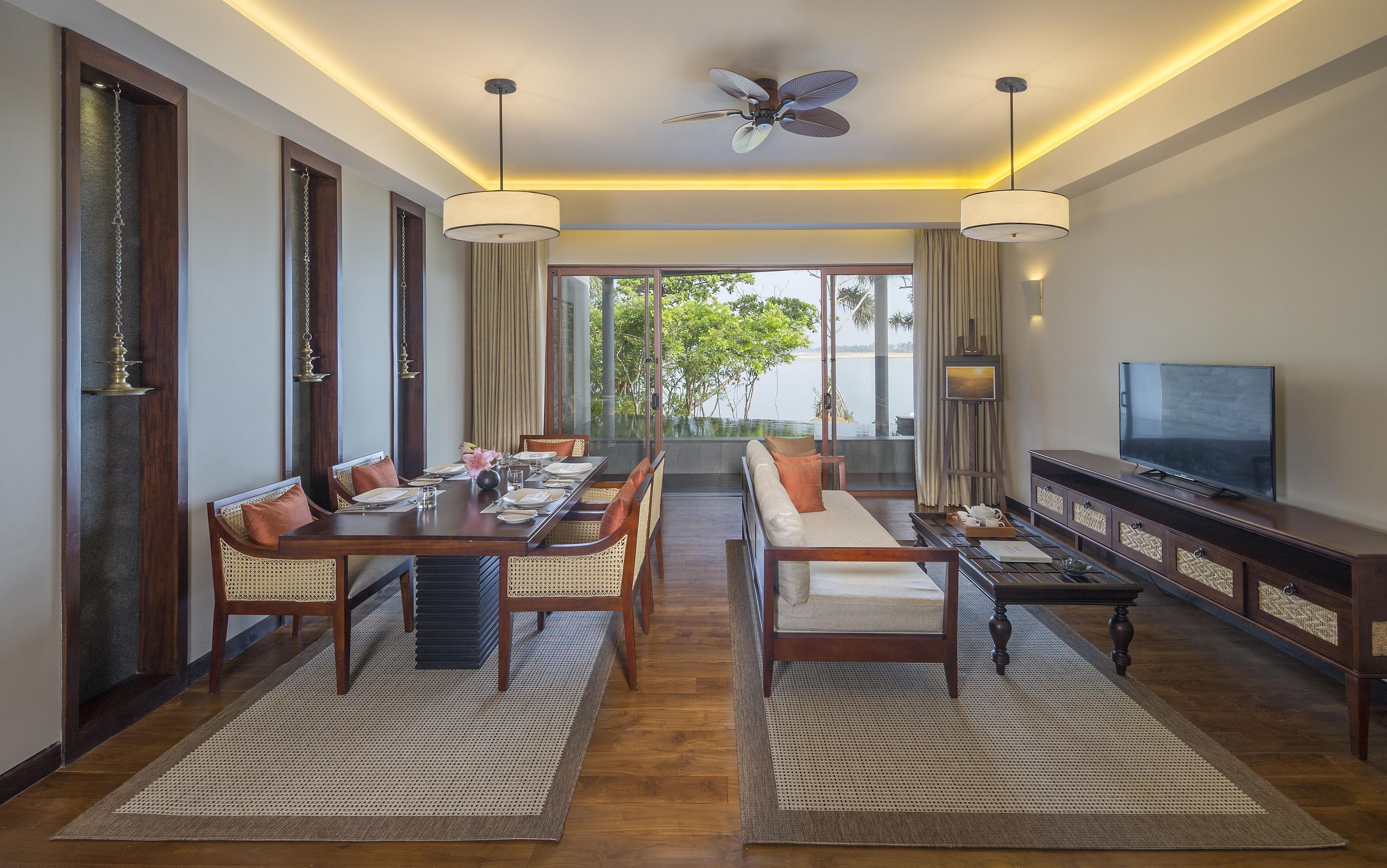 Habitación de hotel con comedor, sofá, televisión y vistas al exterior.