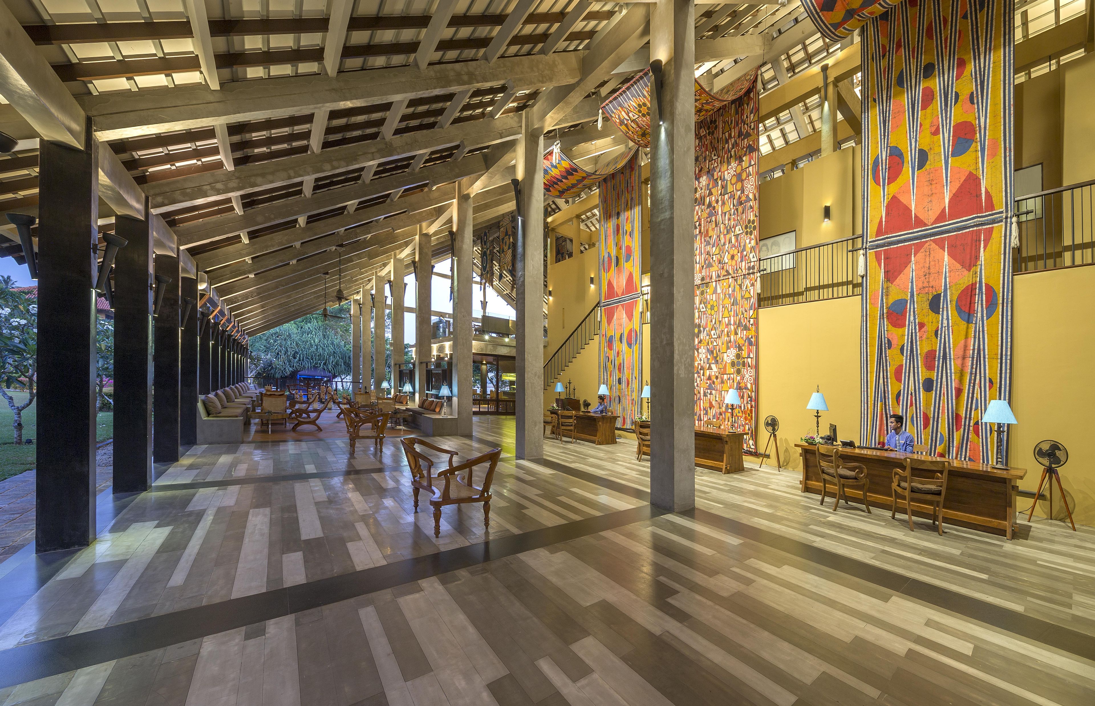 A spacious lobby with a high ceiling, wooden columns, and a patterned wall.