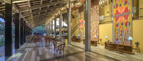 A spacious lobby with a high ceiling, wooden columns, and a patterned wall.