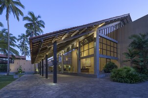Um hotel moderno com galeria coberta, janelas amplas e palmeiras.