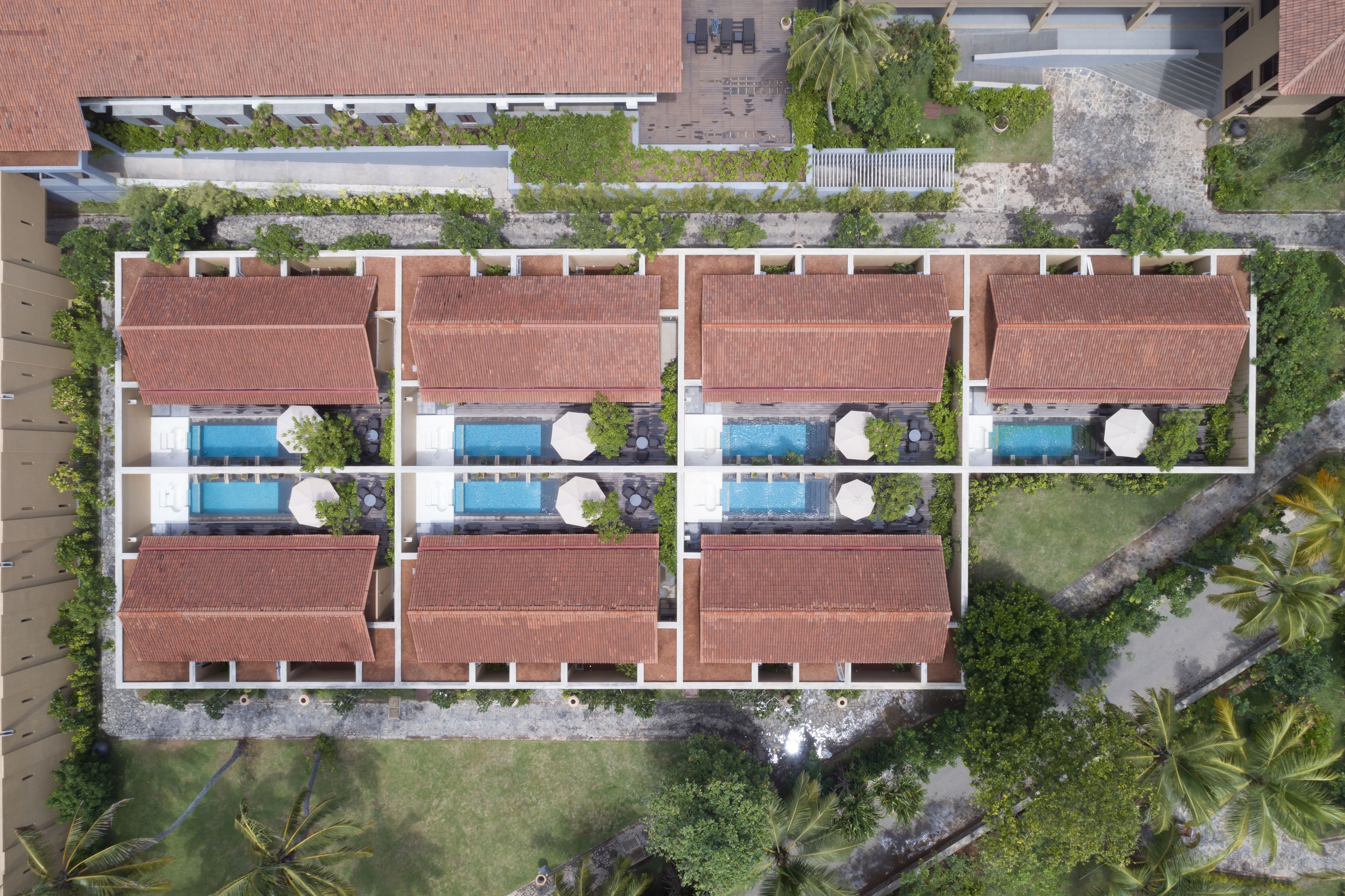 Un resort con sei edifici rettangolari, ognuno dotato di piscina e immerso nel verde.