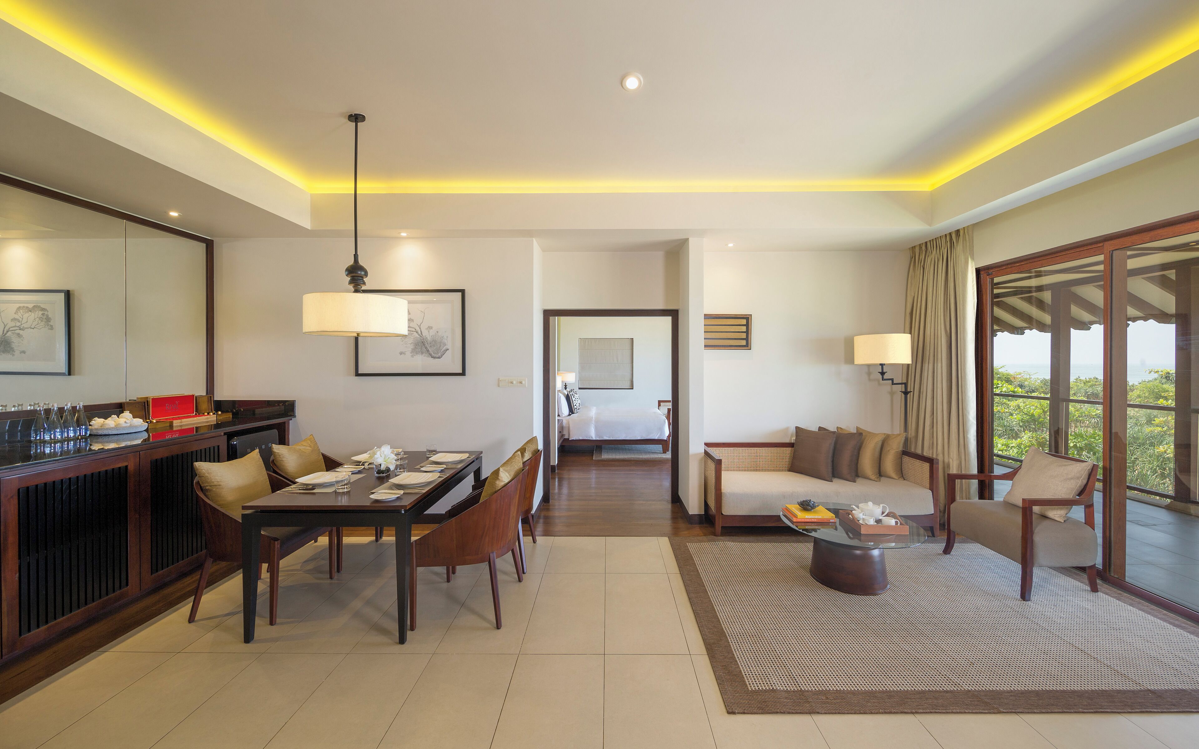 Una habitación de hotel moderna con comedor, sala de estar con sofá y sillones, cama y balcón con vistas.