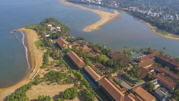 Stunning coastal resort area with buildings nestled among lush greenery and palm trees along a sandy beach.