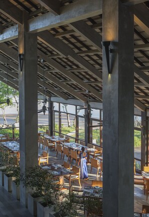 An outdoor dining area with tables and chairs, large concrete pillars, and hanging lights. - Anantara Kalutara Resort (Kalutara)