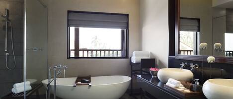 A modern bathroom with a freestanding bathtub, two sinks, a large mirror, and a window with a view.