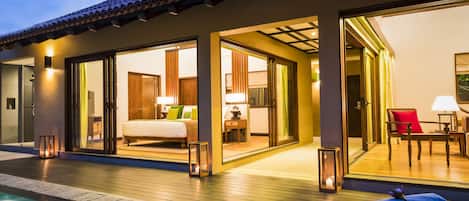 A hotel suite with a private pool, a bedroom with a bed and a sitting area, and a dining area with a table and chairs.