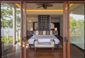 A spacious bedroom with a large bed, a ceiling fan, and a view of lush greenery outside. - Anantara Kalutara Resort (Kalutara)
