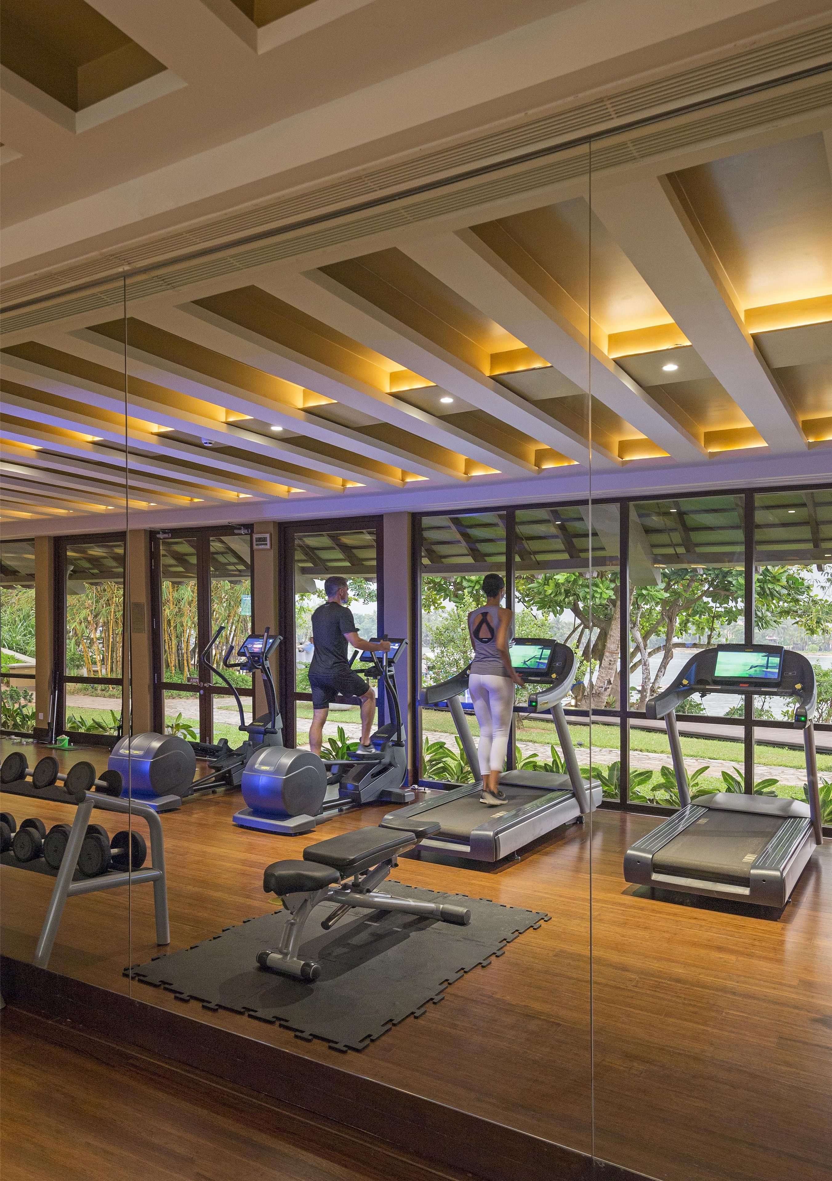 Une salle de sport équipée de tapis de course, d’haltères et d’un banc de musculation.