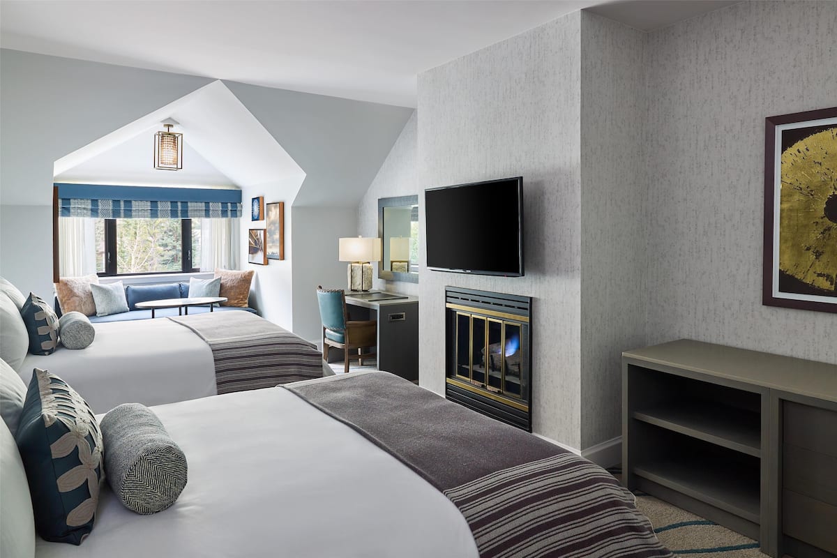 Ein Hotelzimmer mit zwei Betten, einem Fernseher, einem Kamin und einem Schreibtisch.