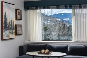 A room with a large window, a sofa, and a table with pinecones.