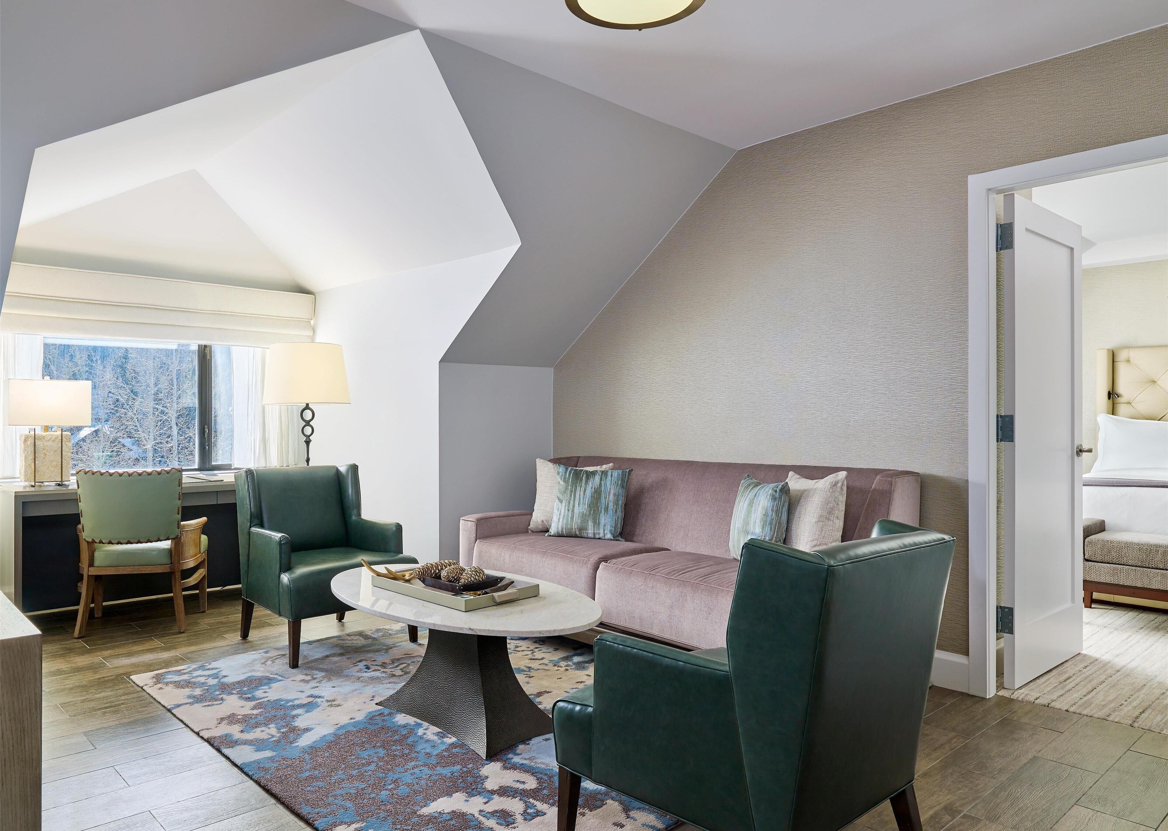 Un salon moderne avec un plafond haut, un canapé, deux fauteuils, une table basse et une lampe.